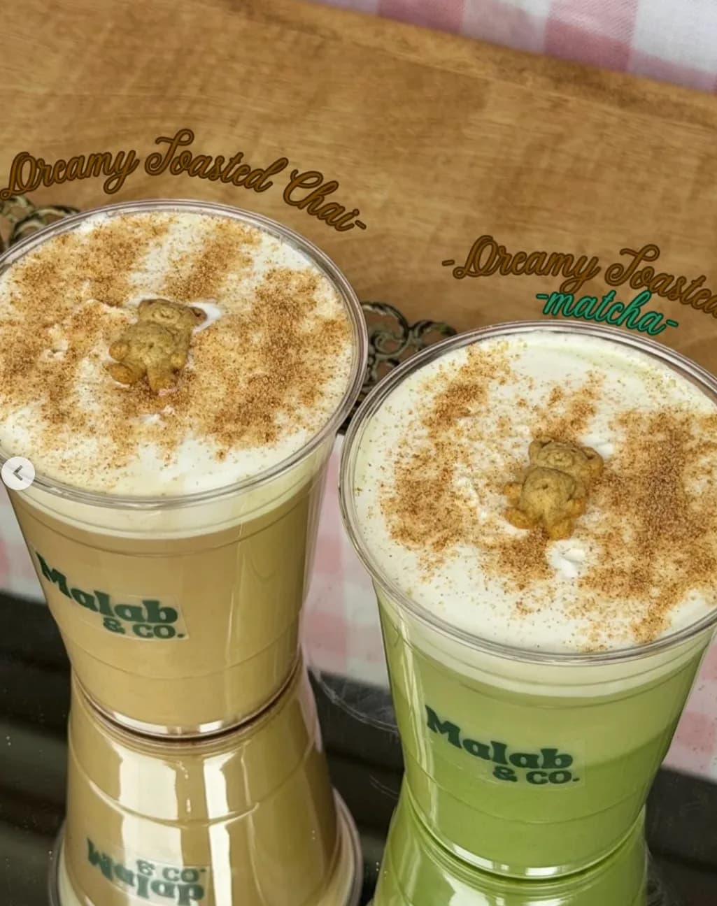 Dreamy Toasted Chai and Matcha side by side, dusted with cocoa and topped with a teddy graham